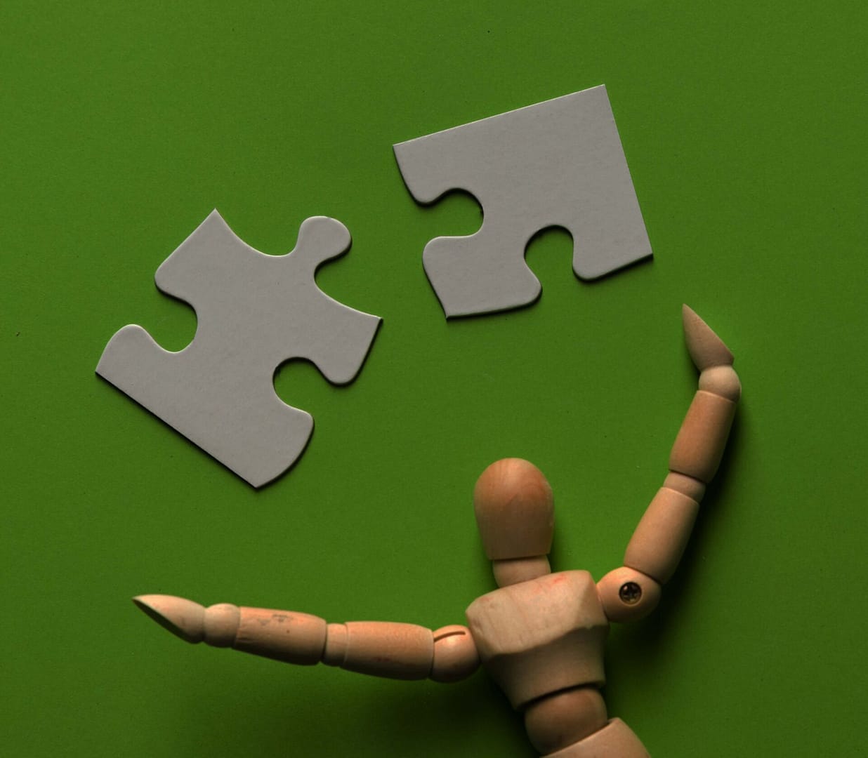 puzzle-piece-with-wooden-human-figure-green-backdrop